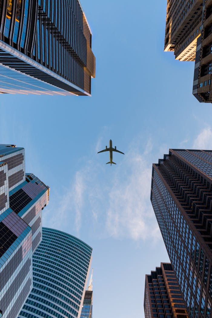 gallery-04 Airplane flies over Chicago's modern skyscrapers against a clear sky, highlighting urban architecture.